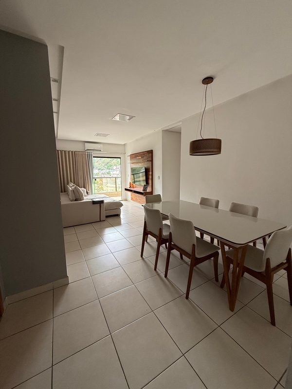 Sala de jantar integrada à sala de estar, com mesa clara e varanda ao fundo