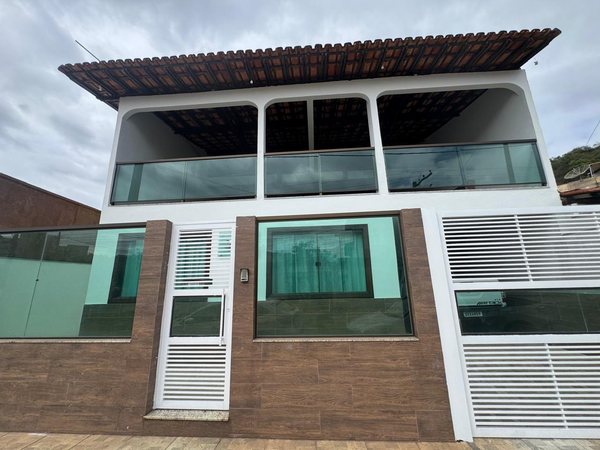 Fachada de casa moderna com dois pavimentos, amplos vidros e muro revestido em porcelanato amadeirado